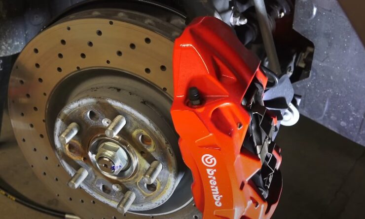 A close-up of a brake disc featuring an orange brake pad resting on its surface